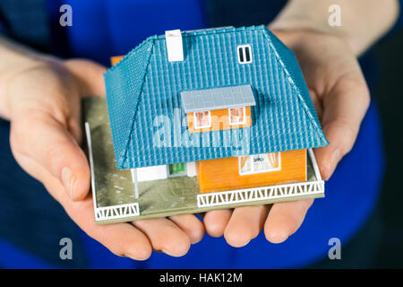 Immobiliare di concetto - piccole dimensioni modello casa di famiglia a womans mani Foto Stock
