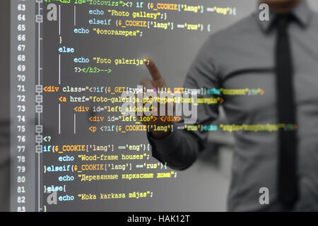 L'uomo puntando su schermo virtuale con sito web codice di programmazione Foto Stock