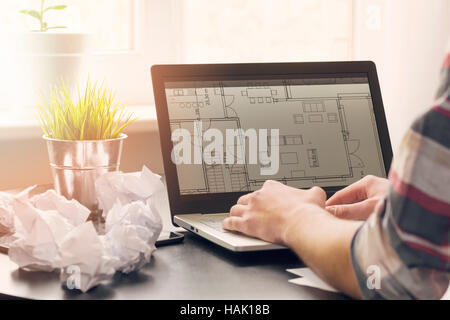 Architetto, interior designer che lavora sul computer portatile con planimetrie Foto Stock