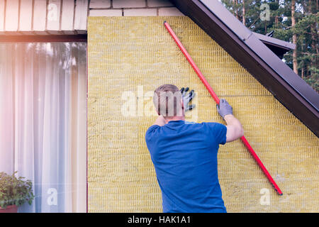 Operaio edile controlla il livello di casa isolata parete Foto Stock