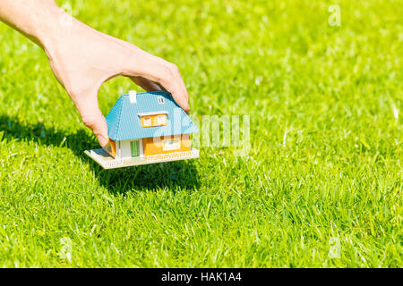 Nuovo concetto di home, mettendo mano casa modello in scala di erba Foto Stock