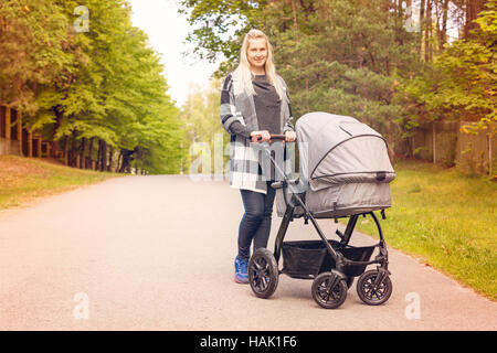 Felice giovane madre con bambino trasporto sulla bellissima giornata autunnale Foto Stock