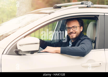 Felice giovane uomo seduto in macchina Foto Stock