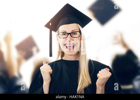 Laurea - happy donna che indossa camice e cappuccio celebrando Foto Stock