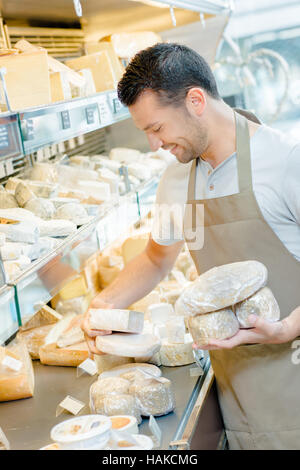 Shop assistant calza ripiano di formaggio Foto Stock