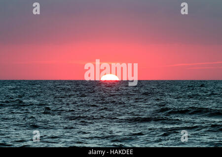 Inghilterra, Broadstairs. Il sorgere del sole sopra il canale inglese. Red Sky. Sun red ball metà risorto. Foto Stock