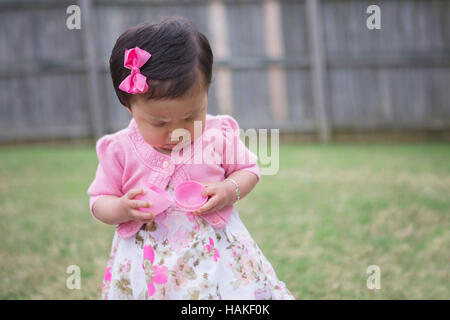 Il Toddler Girl accigliata come lei si apre un vuoto di uovo di Pasqua Foto Stock