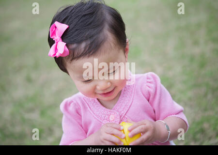 Il Toddler ragazza sorridente mentre lei si apre un uovo di Pasqua Foto Stock