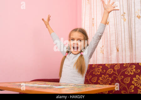 Ragazza felicemente sollevato le sue mani fino a raccogliere immagine del puzzle Foto Stock