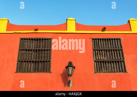 Due finestre e una strada luce su un rosso edificio coloniale nel centro storico di Cartagena, Colombia Foto Stock