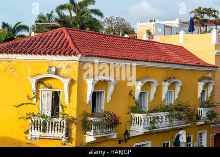 Giallo storico edificio in stile coloniale con fiori di bouganville sui balconi a Cartagena, Colombia Foto Stock