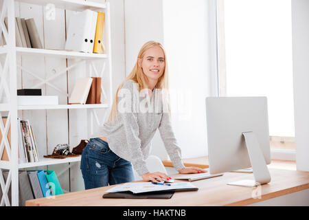 Felice attraente business woman standing e lavorare con il computer in ufficio Foto Stock