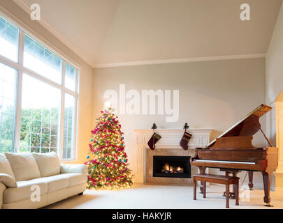 Albero di natale in soggiorno con caminetto e pianoforte luminose durante il giorno. Foto Stock