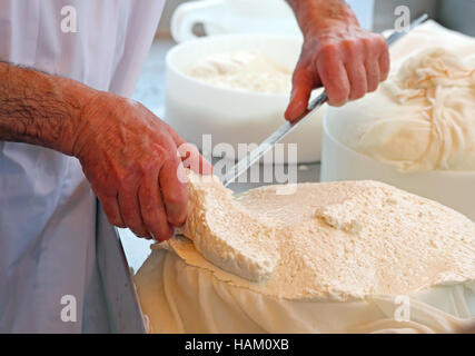 L'uomo tagli con un coltello affilato un formaggio cucinati freschi Foto Stock