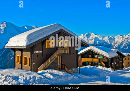 Chalet Svizzero con uno spesso strato di neve sul tetto con Fletschhorn, Bettmeralp, Vallese, Svizzera Foto Stock