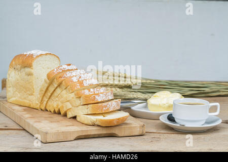 Il pane su legno di trinciatura e di caffè nero e burro sul tavolo di legno. Foto Stock