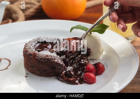 Concetto: ristorante menu, mangiare sano, fatti in casa, golosi, golosità. Piastra bianca con cioccolato fondente con fragole e gelati su un confuso Foto Stock