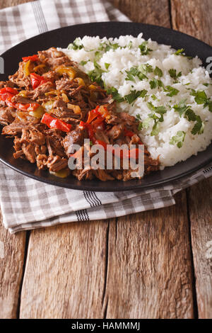 Cibo messicano Ropa vieja: stufato di manzo con salsa al pomodoro con verdure e guarnire il riso su una piastra di close-up verticale. Foto Stock