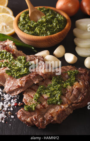 Cucina argentina: grigliate di carne di manzo con salsa chimichurri macro sul tavolo. In verticale Foto Stock