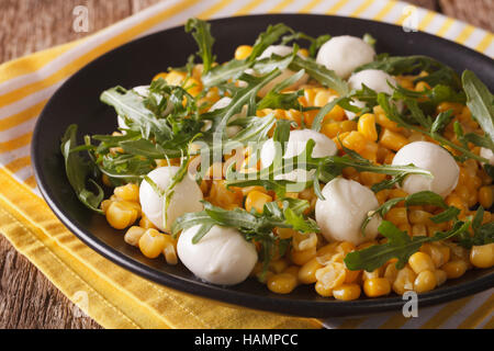 Insalata dietetica di mais, baby mozzarella e rucola close-up su una piastra orizzontale. Foto Stock