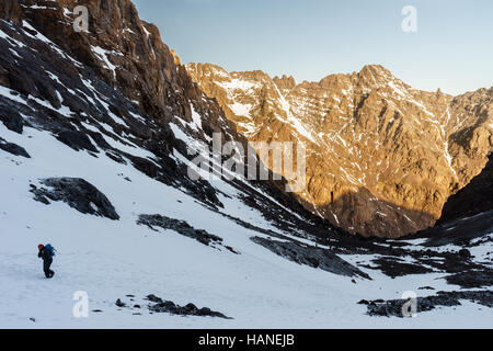 Un alpinista caucasica uomo cammina attraverso la neve per raggiungere la cima di Jbel Toubkal di sunrise Foto Stock