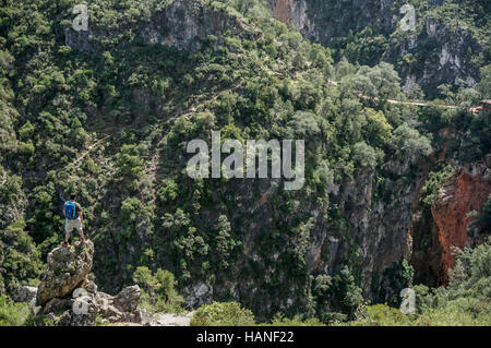 Una montagna escursionista osserva da una roccia presso la scogliera la formazione geologica del ponte di Dio nelle montagne del riff in Marocco Foto Stock