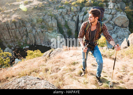 Viaggiatore con zaino sorge vicino al canyon. guardando lontano. a piena lunghezza immagine Foto Stock