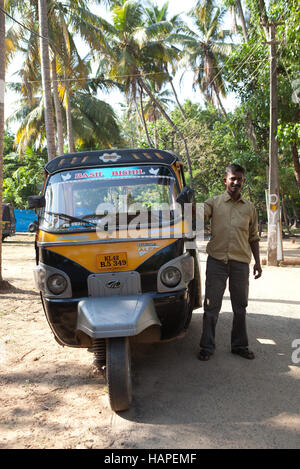 Conducente in piedi accanto alla sua auto rickshaw taxi in Cherai Beach, India Foto Stock