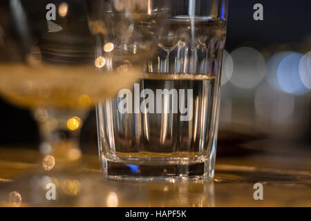 Ritratto di close-up di un bicchiere di acqua che è mezzo pieno in piedi su un marrone tavolo in legno alla vigilia di Natale Foto Stock