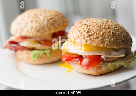 Pancetta, uova e pomodoro panini sulla piastra bianca, vista ravvicinata Foto Stock