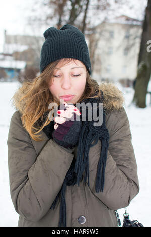 Donna riscaldare le mani in coperta di neve park Foto Stock