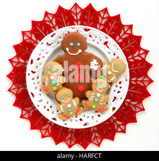 Carino poco decorata gingerbread gli uomini sulla piastra bianca e rossa tappeto di feltro in formato quadrato dal tettuccio Foto Stock