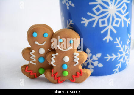 Carino poco decorata gingerbread gli uomini con il simbolo del fiocco di neve la tazza di cioccolata calda per un Natale di trattare Foto Stock