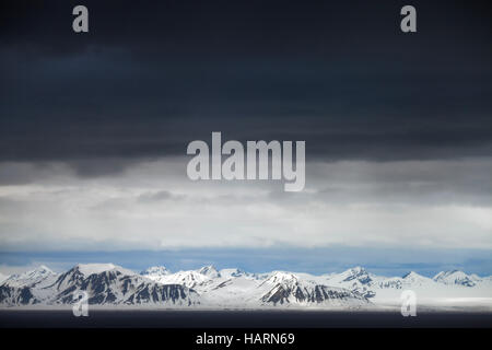 Nero pioggia nuvole sopra montagne coperte di neve lungo Isfjorden, il secondo più lungo il fiordo a Spitsbergen / Svalbard Foto Stock