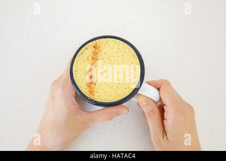 Mani tenendo la curcuma latte latte Foto Stock