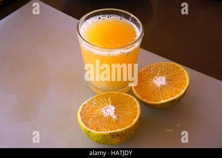 Un bicchiere di spremuta di mandarino succo con i tangerini tagliati a metà Foto Stock