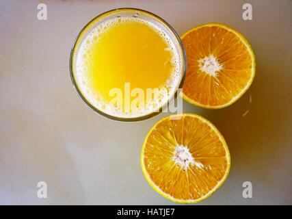 Un bicchiere di spremuta di mandarino succo con i tangerini tagliati a metà Foto Stock