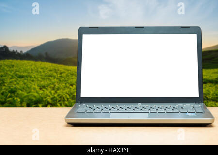 Computer portatile con schermo vuoto sul tavolo con blur natura verde in background. Concetto tecnologico. Foto Stock