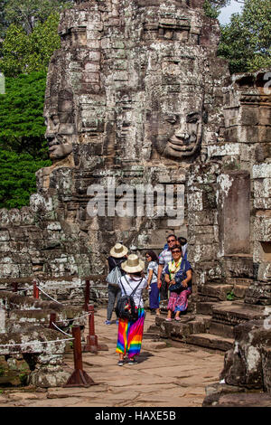 Antica facce di pietra arenaria a Prasat in Bayon Angkor Thom guardare giù a turisti che visitano il complesso tempio in Cambogia. Foto Stock