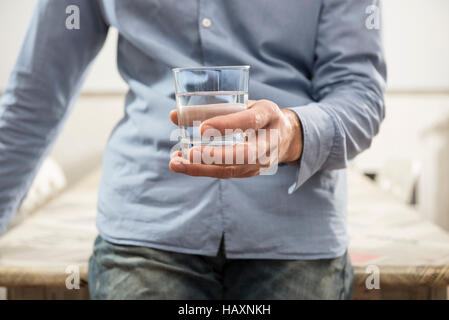 Uomo che tiene in mano un bicchiere di acqua Foto Stock