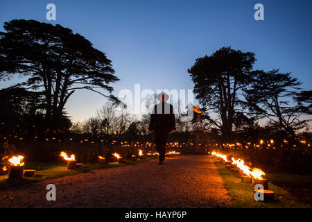 Un maschio in silhouette agaisnt il cielo darkeneing passeggiate attraverso i percorsi antincendio del giardino delle rose a Blenheim Palace come agrdens vengono illuminate con luci di festa per il natale. Foto Stock