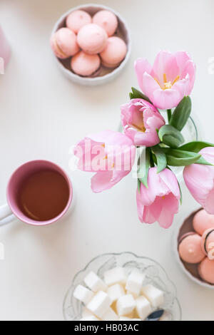 Molla dello sfondo. Dolci e tè su un tavolo con il rosa tulipani. Foto Stock