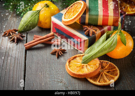 Decorazione di natale con mandarini, doni, cannella, anice stelle, essiccato fettine di arancia e rami di abete rosso su uno sfondo di legno. Foto Stock