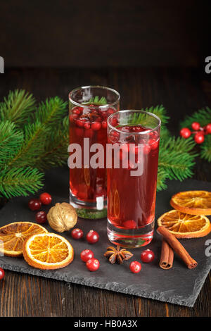 Natale cocktail a base di mirtillo palustre decorate con bastoncini di cannella, anice stelle, secco fettine di arancia e rami di abete Foto Stock