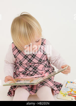 Bambina girando le pagine di un libro di fotografia Foto Stock