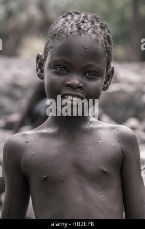 EPUPA FALLS, NAMIBIA, GENNAIO 7: Ritratto di un giovane bambino africano dalla gente di Himba che guarda la macchina fotografica. Foto Stock