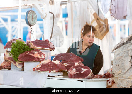 CUSCO, PERÙ, GENNAIO 15: Carne rossa fresca in piedi sul macellaio stalla con la donna peruviana sfocata che lavora in background al mercato alimentare di Cusco Foto Stock