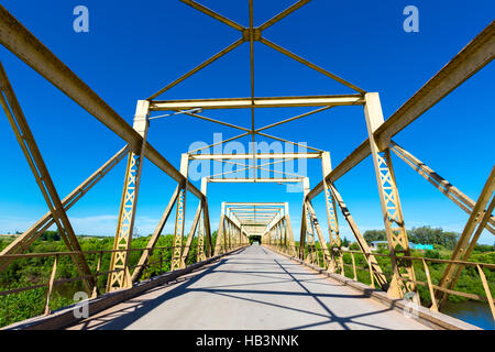 La strada attraverso il vecchio metallo giallo bridge tunnel con cielo blu chiaro in Uruguay Foto Stock