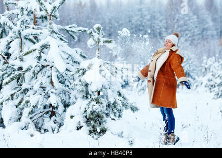 Giovane donna incinta indossando vestiti caldi avendo divertimento sul bellissimo inverno nevoso giorno Foto Stock