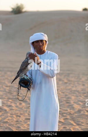 Giovane uomo arabo tenendo un falco nel deserto vicino a Dubai, Emirati arabi uniti Foto Stock